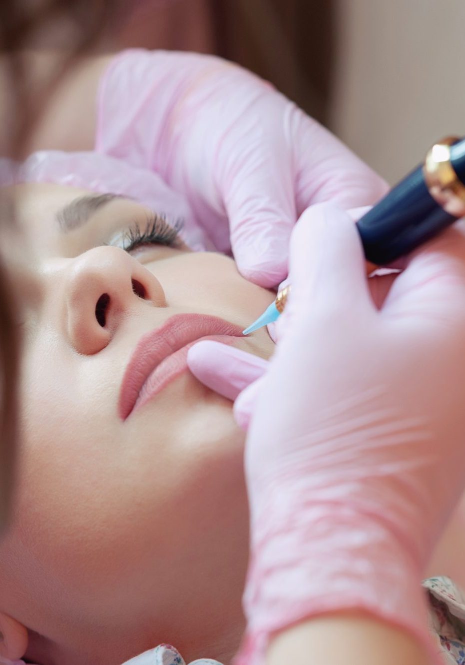 A young woman lies and gets a make-up of her eyebrows in a beauty salon. The use of permanent makeup on the eyebrows. The master works with the eyebrows. Semi-permanent makeup.