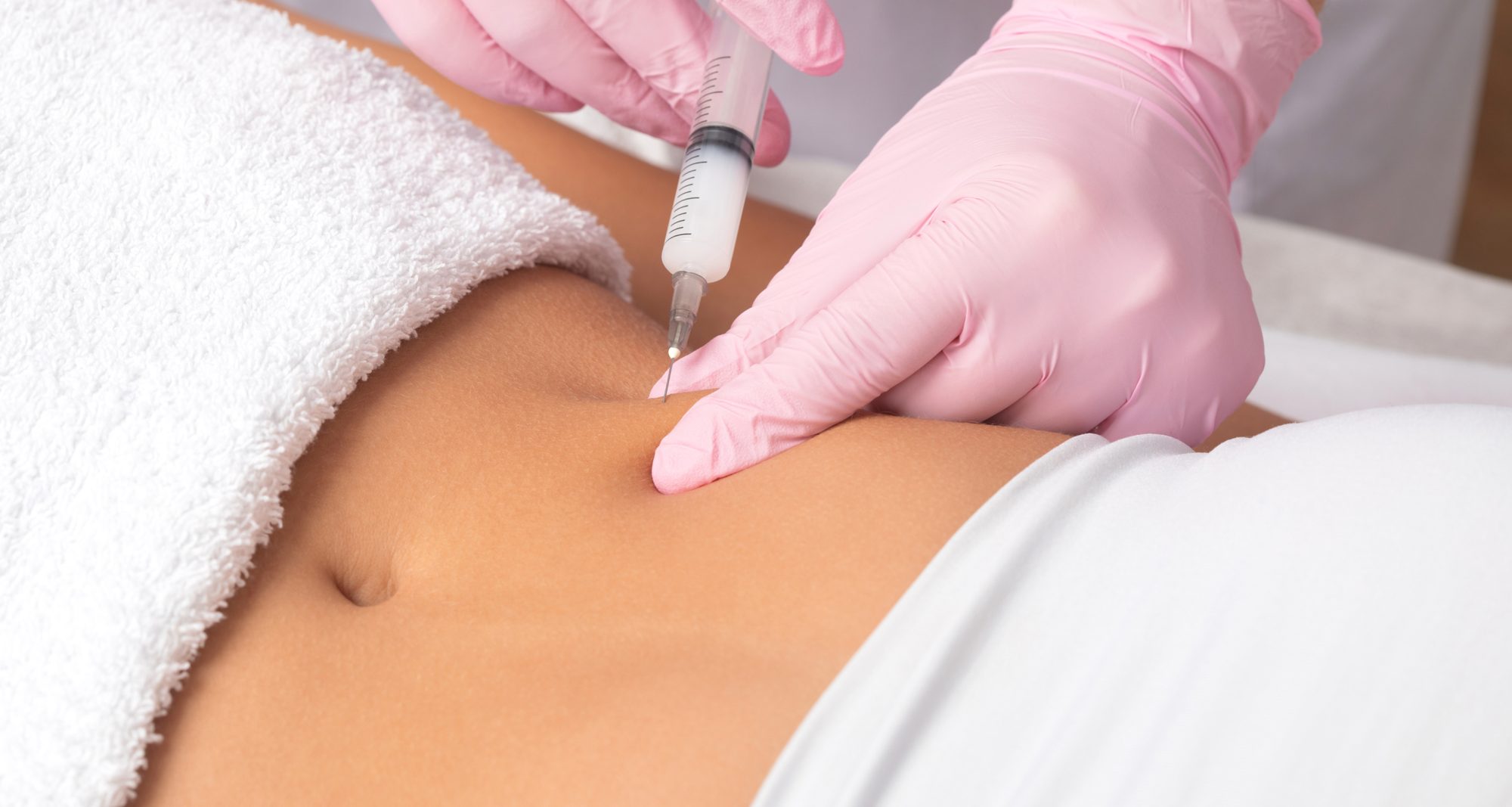 A doctor of aesthetic cosmetology makes lipolytic injections to burn body fat on a woman's stomach and body. Female aesthetic cosmetology in a beauty salon.